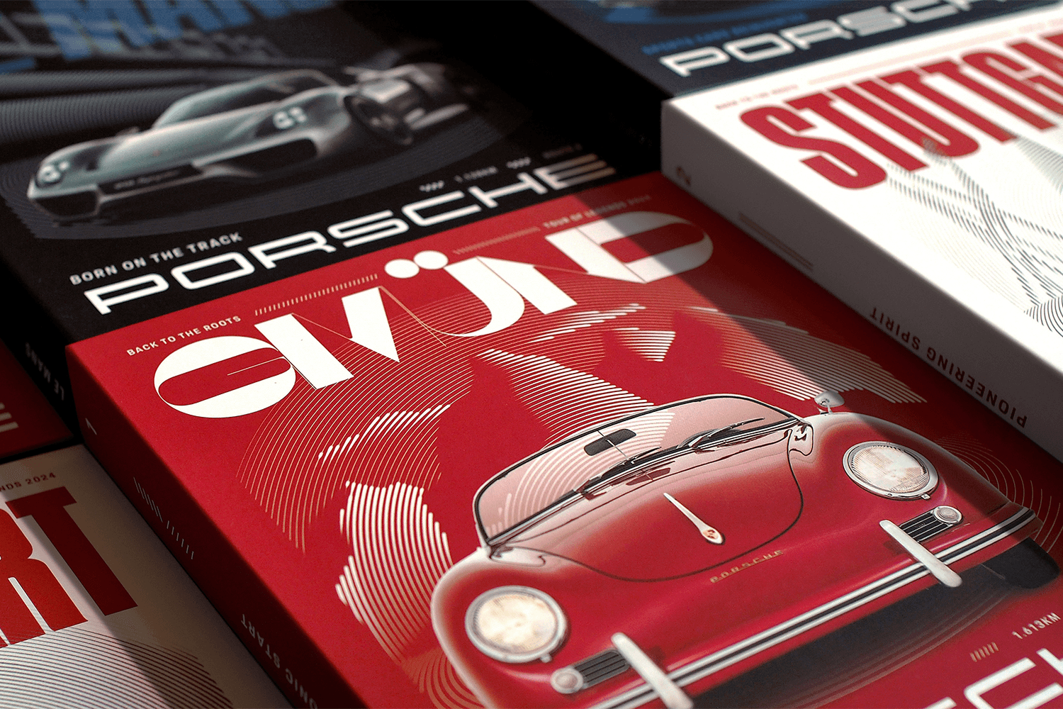 Stack of automotive magazines with a red cover featuring an illustrated vintage Porsche and visible "Porsche" headlines.
