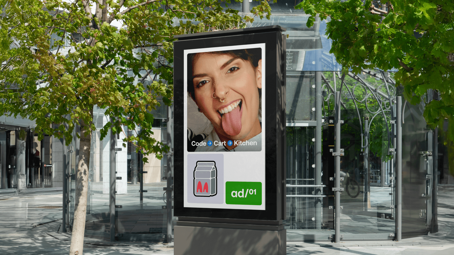 Digital billboard in a glass city plaza displaying a close-up of a smiling woman sticking out her tongue with app icons.