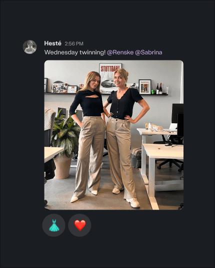 Sabrina and Renske in the office wearing matching beige wide-leg pants and black tops, smiling with arms around each other in front of desks and plants.