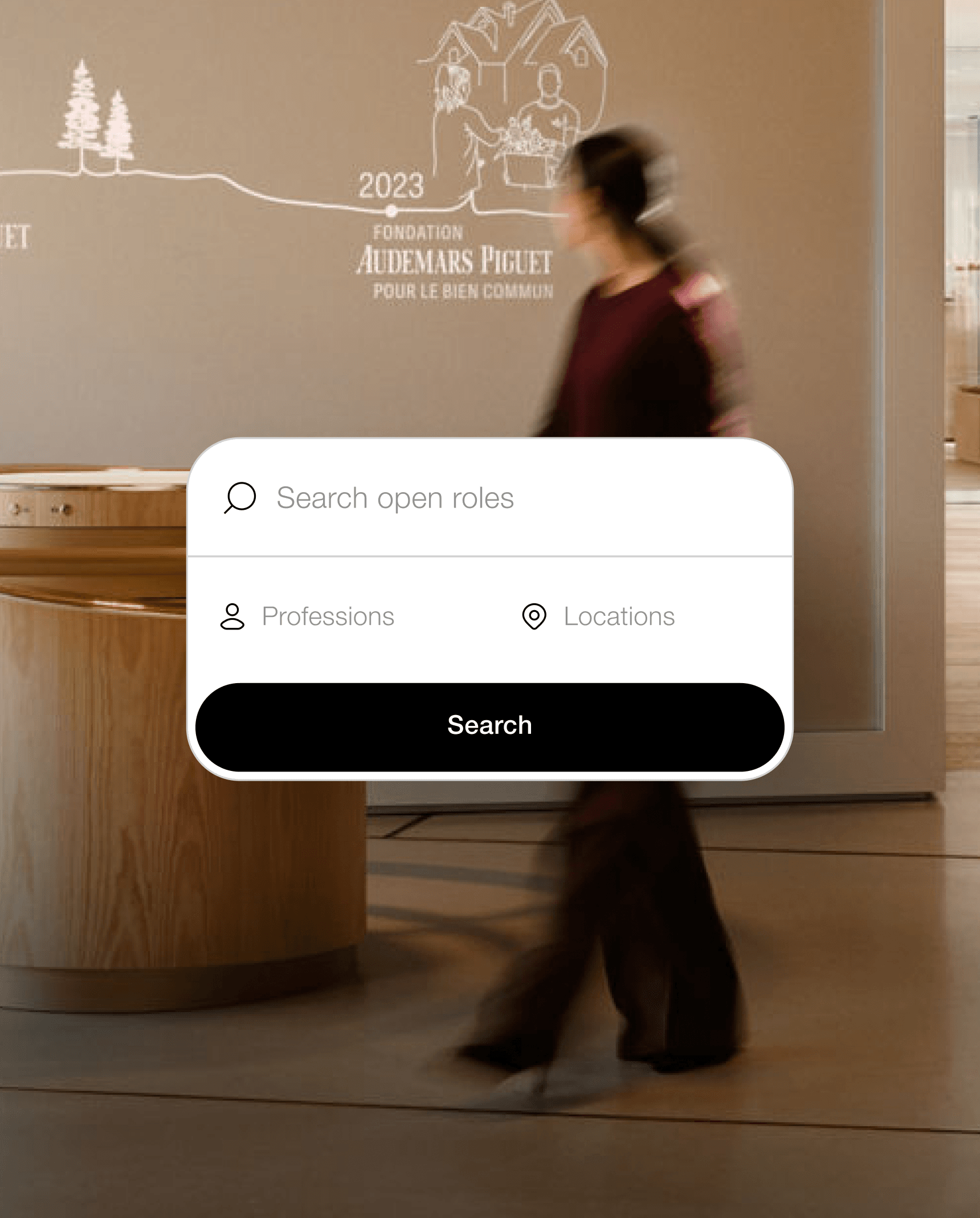Blurry person walks past a wooden display in a lobby with a floating job-search box overlay reading "Search open roles."
