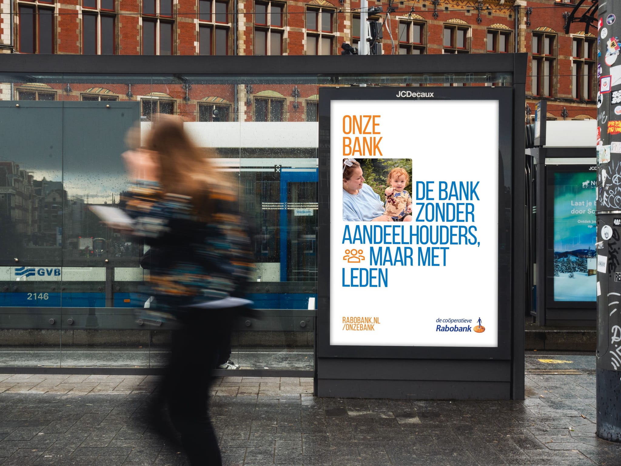 Blurred pedestrian passing a tram-stop ad display featuring a Dutch Rabobank poster reading "Onze Bank."