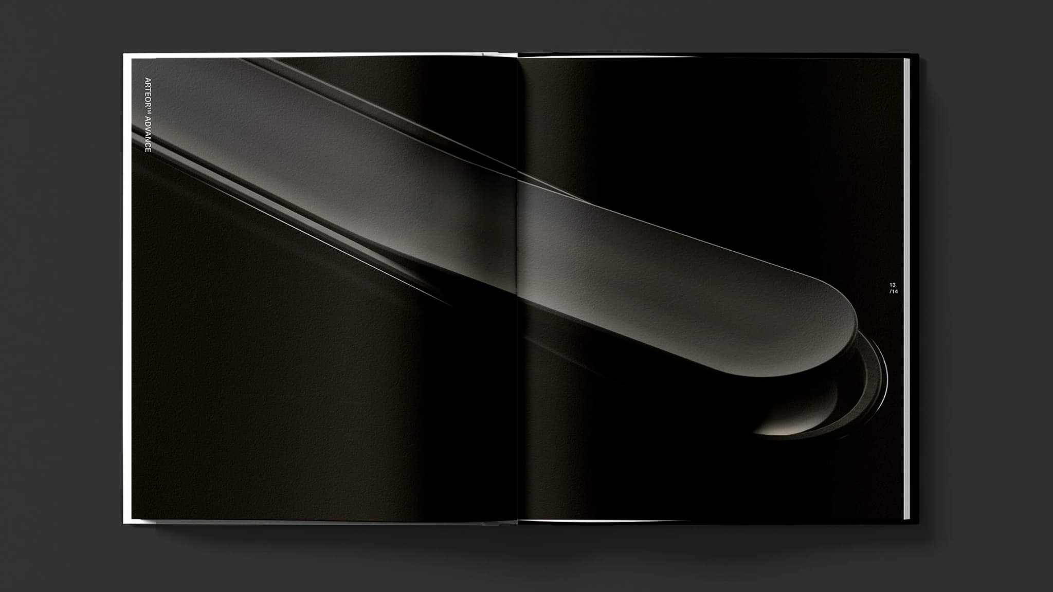 An open magazine displays abstract black and dark gray shapes on both pages, creating a sleek, modern design.