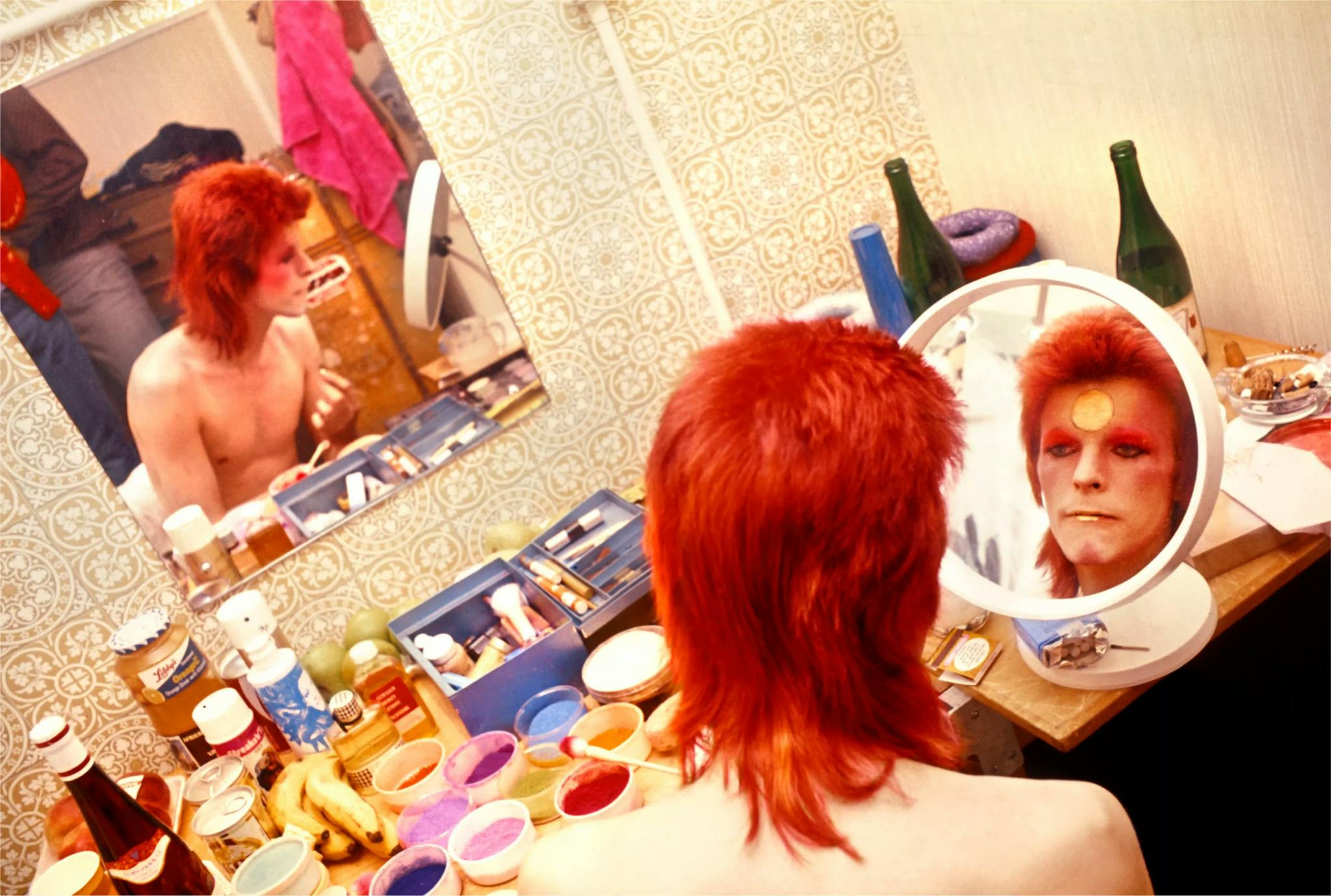David bowie putting make-up in front of a mirror